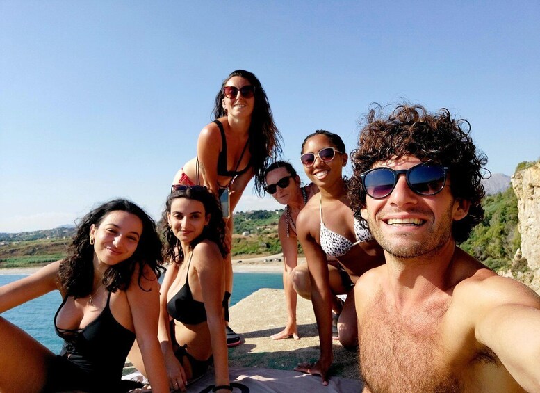 A group of people at a beach with a clear sky and a body of water in the background. 4