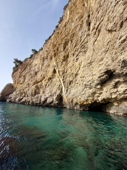 A coastal cliff with clear turquoise water. 2