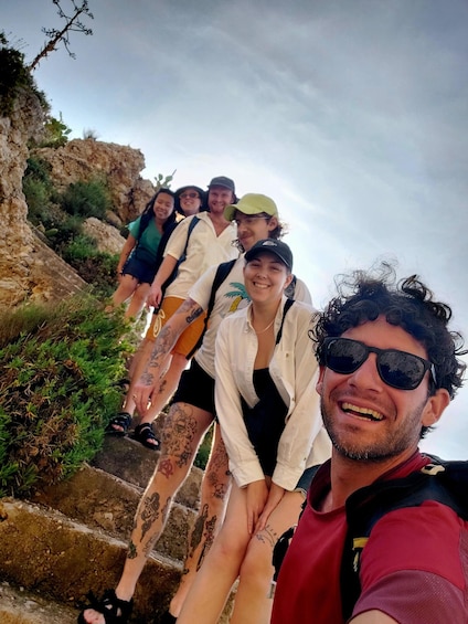 A group of people hiking up a rocky trail with greenery on the sides. 5