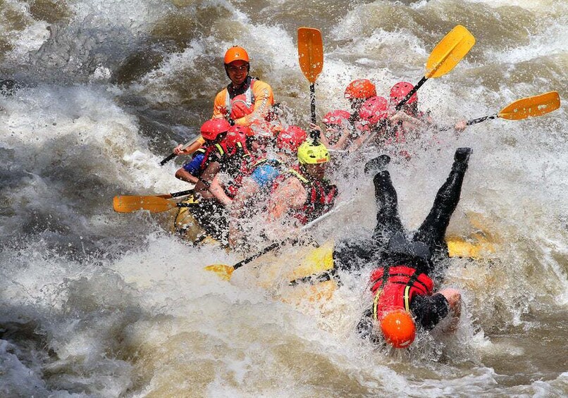 A group of people in a white raft navigating through turbulent water. 4