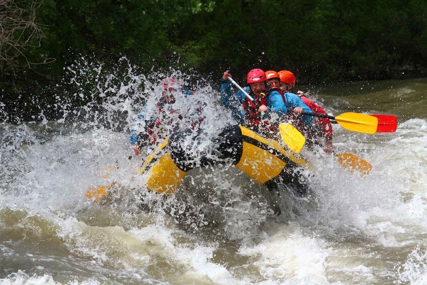 Two people in a yellow kayak navigating through a river with splashes. 1