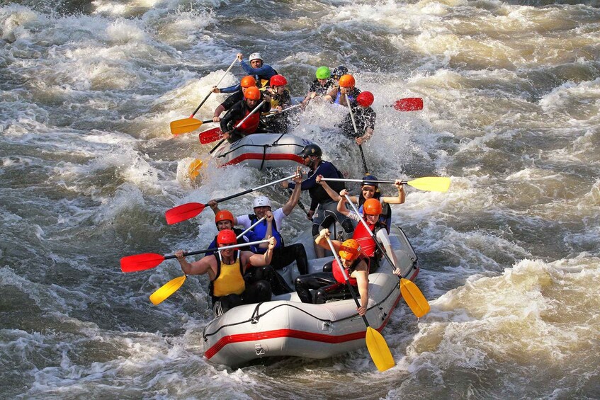 A group of people in a white inflatable raft navigating through rough, white water rapids. 3