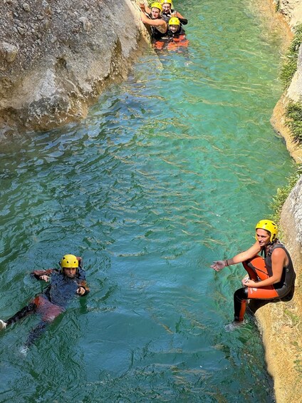 People in a river wearing helmets and life jackets. 2