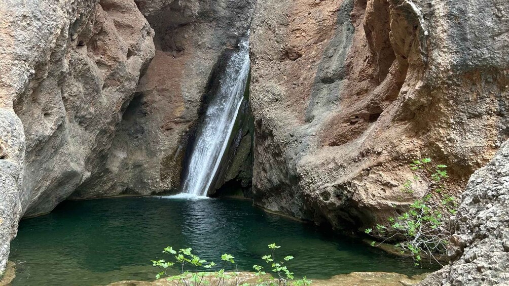 A waterfall cascading into a pool surrounded by rocky cliffs. 3