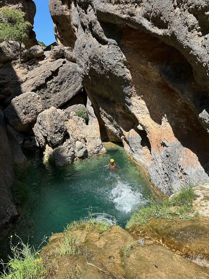 A person swimming in a natural pool surrounded by rocky cliffs. 4