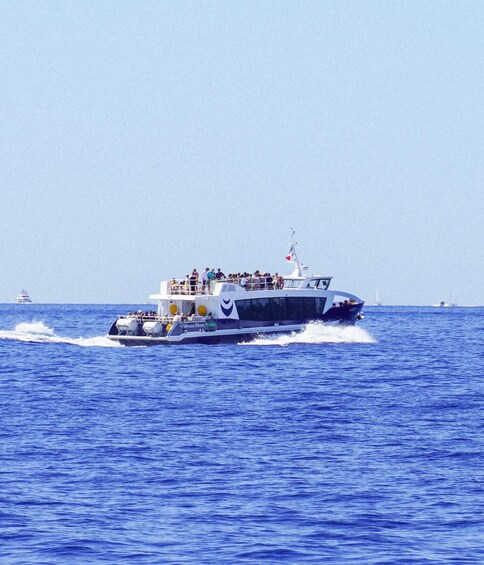 A large boat with passengers, moving through a blue ocean. 2