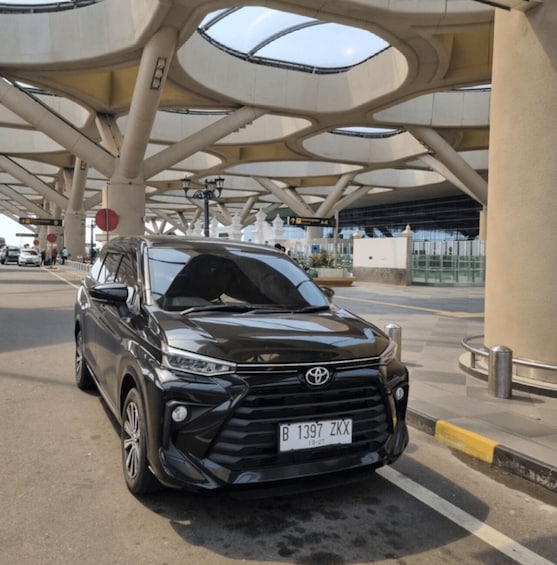A black Toyota SUV at a toll booth with a distinctive modern canopy structure. 3