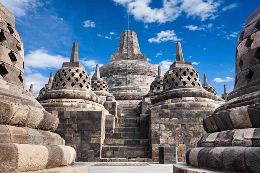 A temple complex with multiple stone structures and a central staircase leading to a large, tiered building. 1
