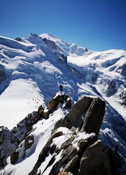 A snowy mountain landscape with rocky outcrops and a clear blue sky. 2
