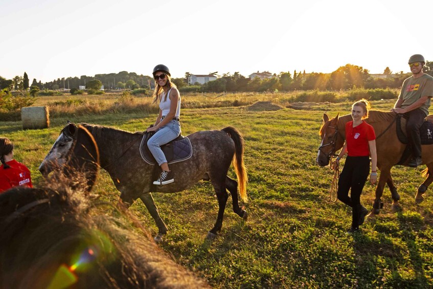 A person riding a horse in a grassy field with hay bales and trees in the background. 4
