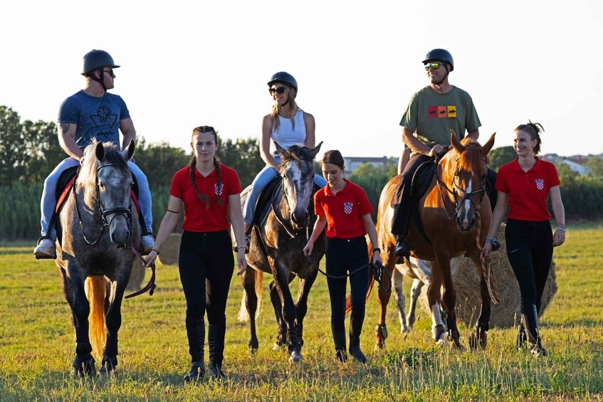 A group of people on horseback in a grassy field. 2