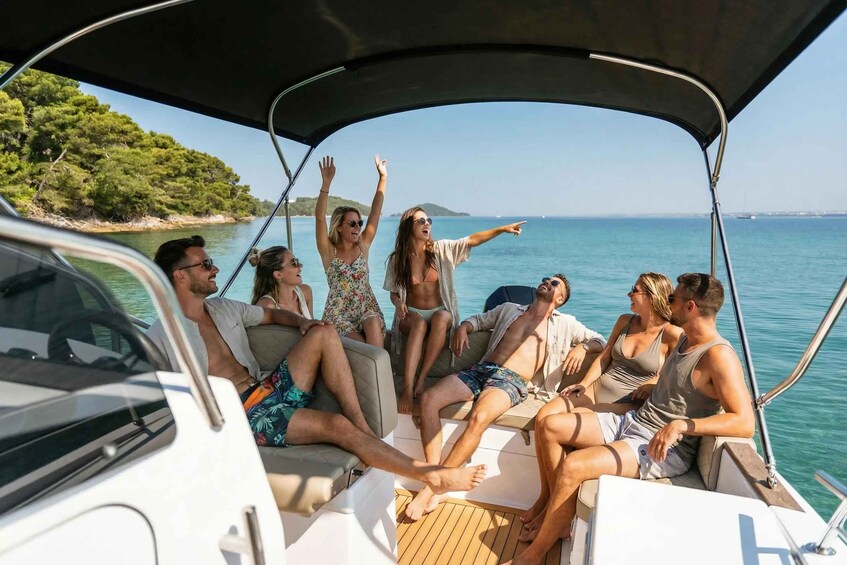 A group of people on a boat with a clear view of the sea and a coastline with trees. 1