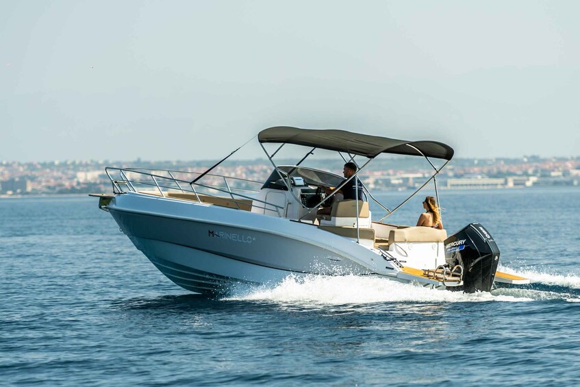 A speedboat with a canopy, a woman, and a cityscape in the background. 5