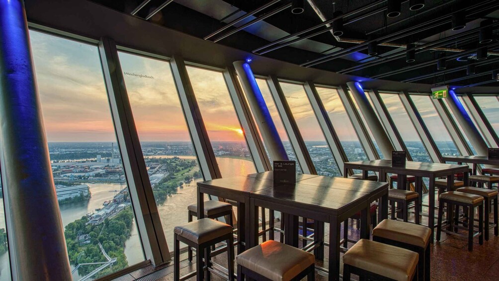 A restaurant with large windows offering a view of a river and cityscape during sunset. 4