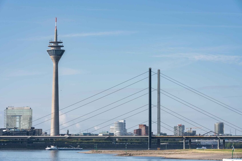 A cable-stayed bridge, a tall tower, and a river with a boat. 2