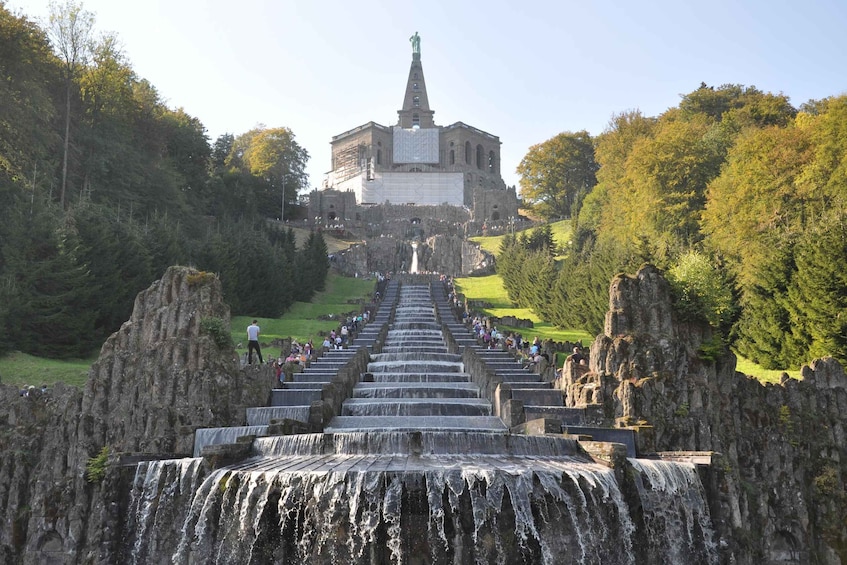 A waterfall leading to a castle with a statue on top. 1