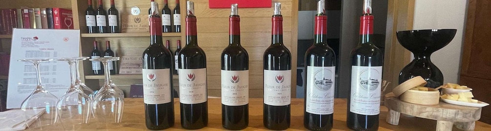 A wine tasting event with several bottles of wine and glasses on a wooden table. 4