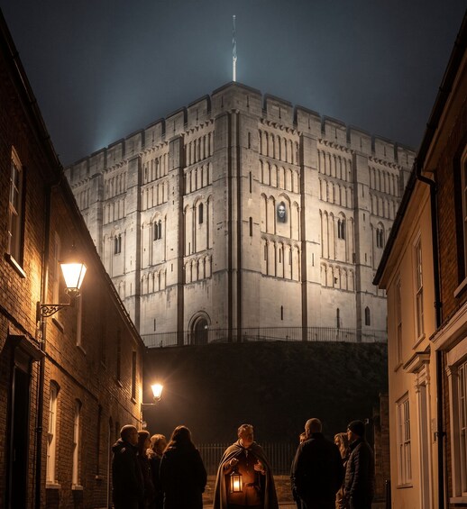 A group of people standing in front of a large, illuminated building with arched windows and a central tower. 3