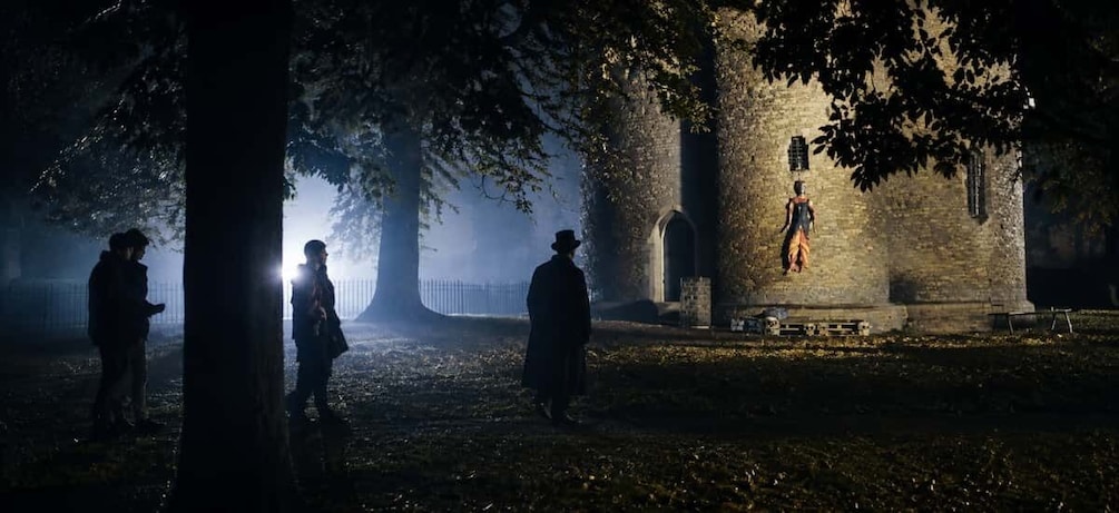 A foggy cemetery with tombstones and a person hanging from a tree. 1