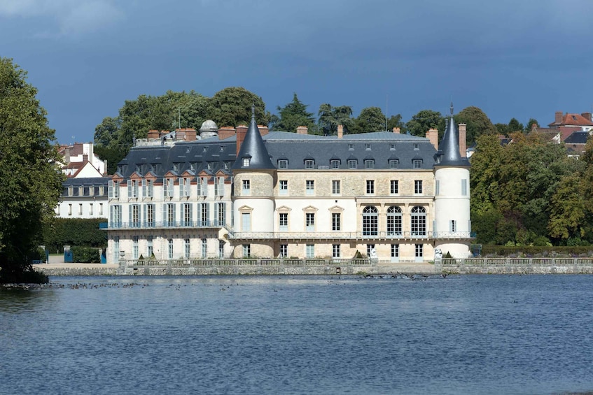 A historic building with multiple towers and a river in the foreground. 2
