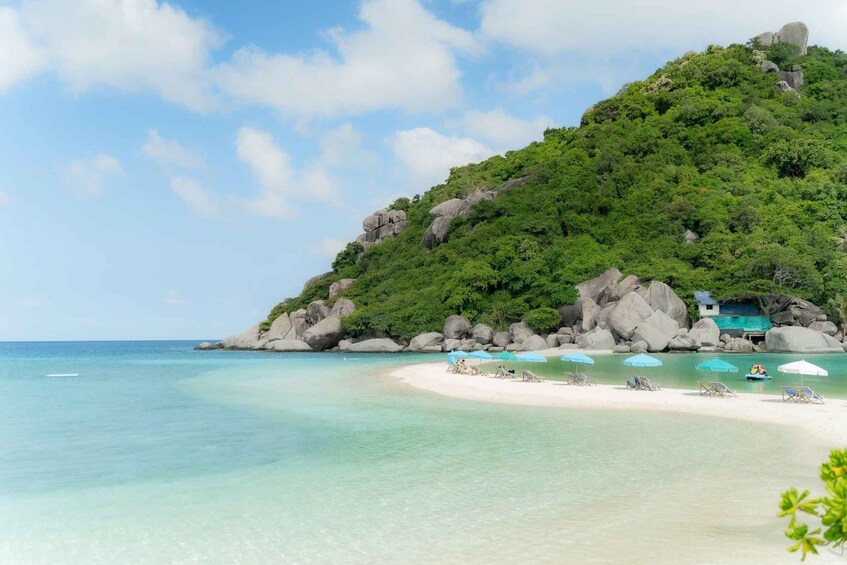 A tropical beach with clear turquoise waters, white sand, and lush green hills. 2
