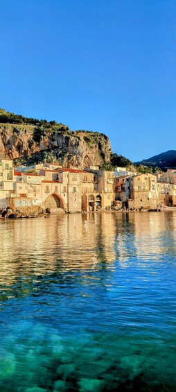 A coastal town with buildings, a bridge, and clear blue water. 1
