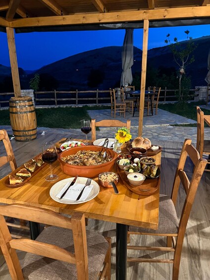 An outdoor dining area with a wooden table set for a meal, surrounded by chairs. 1