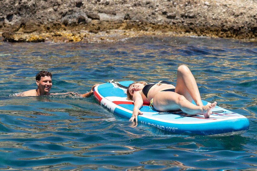 Two people on a blue and red floating board in the water. 2