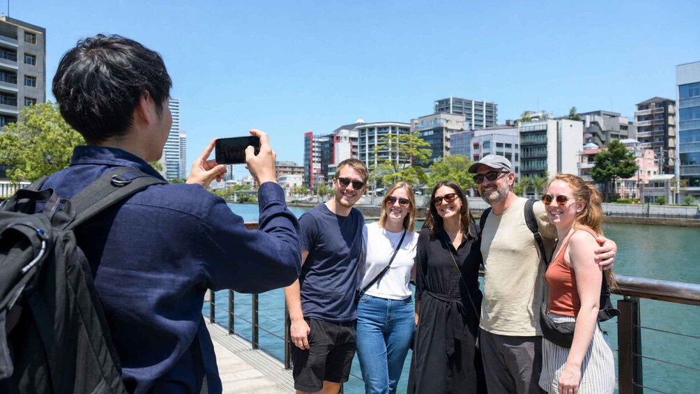 A group of people taking a photo on a bridge with a cityscape in the background. 5