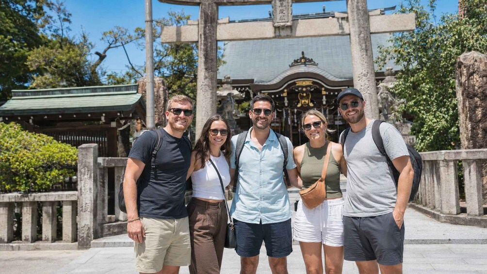 A group of people standing in front of a traditional building with a green roof and stone pillars. 4