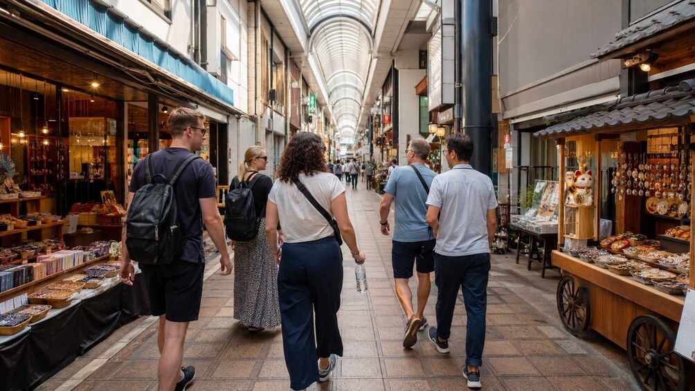 A pedestrian walkway with shops on either side, a covered ceiling, and people walking. 5