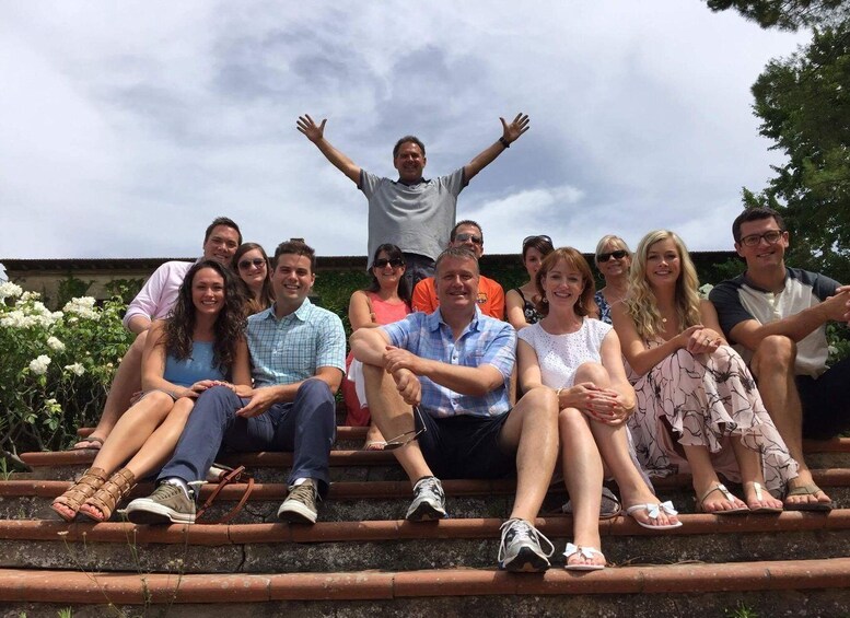 A group of people sitting on outdoor steps with a cloudy sky in the background. 1