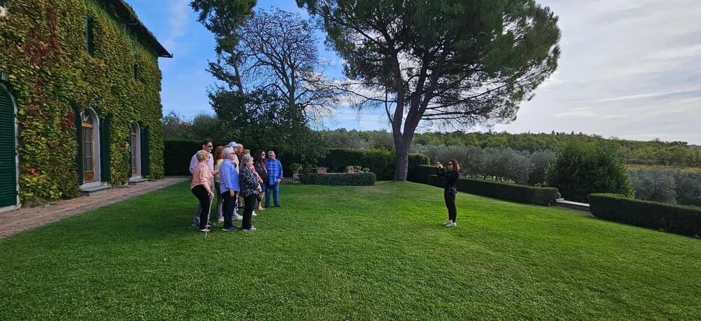 A group of people standing on a well-manicured lawn in front of a building with green ivy. 3