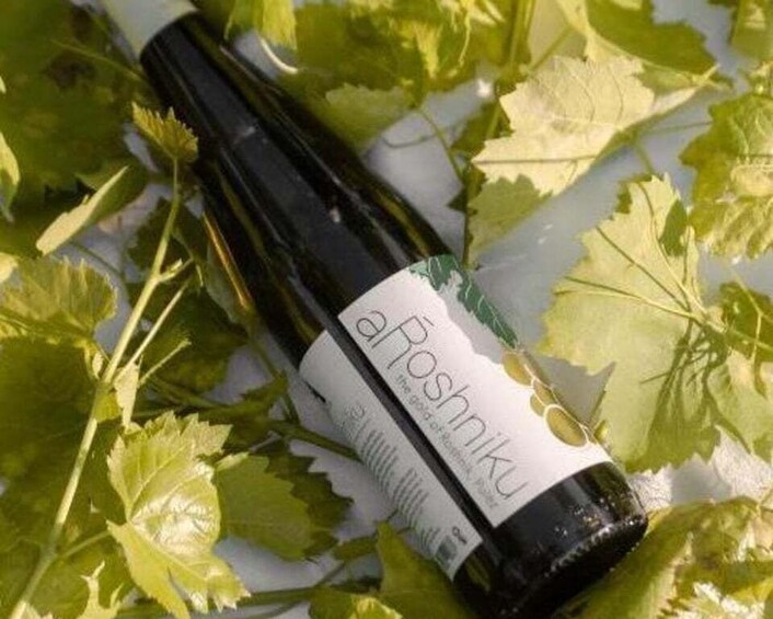 A bottle of wine with a label, surrounded by green leaves. 3