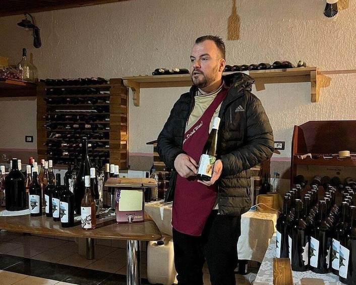 A man in a wine cellar holding a bottle of wine. 2