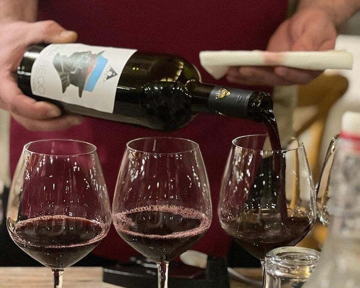 A person pouring wine into glasses. 1