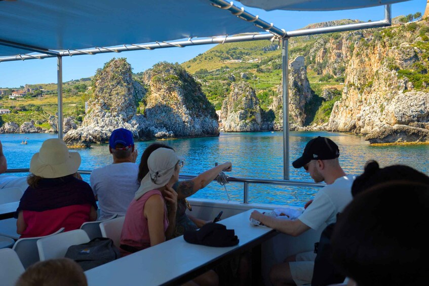 A group of people on a boat with a rocky coastline in the background. 4