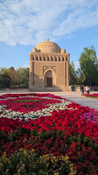 A historic building with a dome and arched entrance, surrounded by a vibrant flower garden. 3
