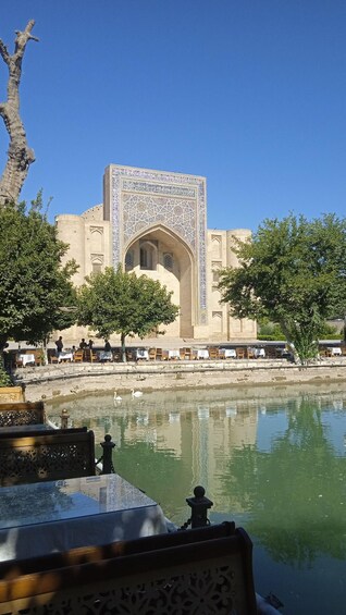 A historic building with intricate tile work, a reflective water body, and surrounding trees. 2
