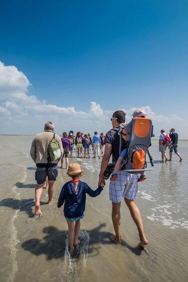 A group of people walking along a beach, some carrying backpacks. 3