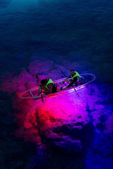 Two people in a kayak on a body of water with colorful lighting. 3