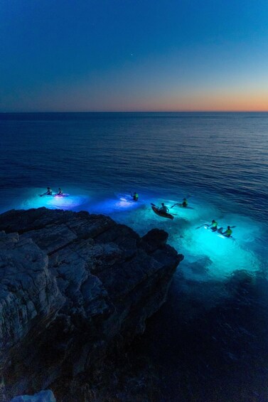 Kayakers on a rocky coastline at dusk. 2
