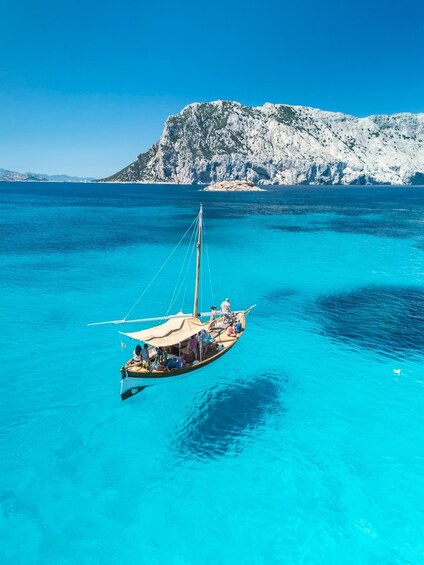 A boat on turquoise sea with a rocky mountain in the background. 2