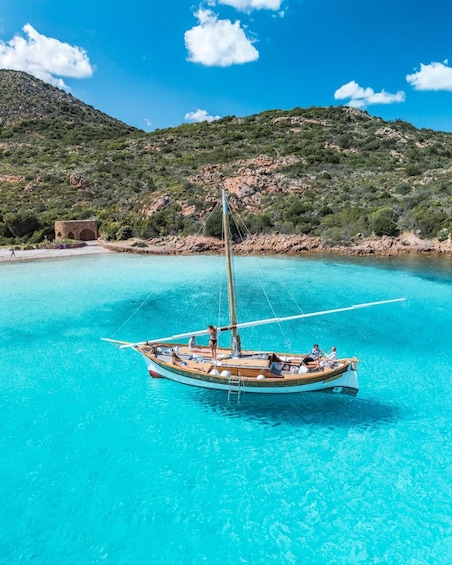 A boat anchored in clear turquoise water with a mountainous backdrop. 4