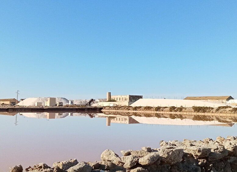 A calm body of water reflecting buildings and a clear sky. 3
