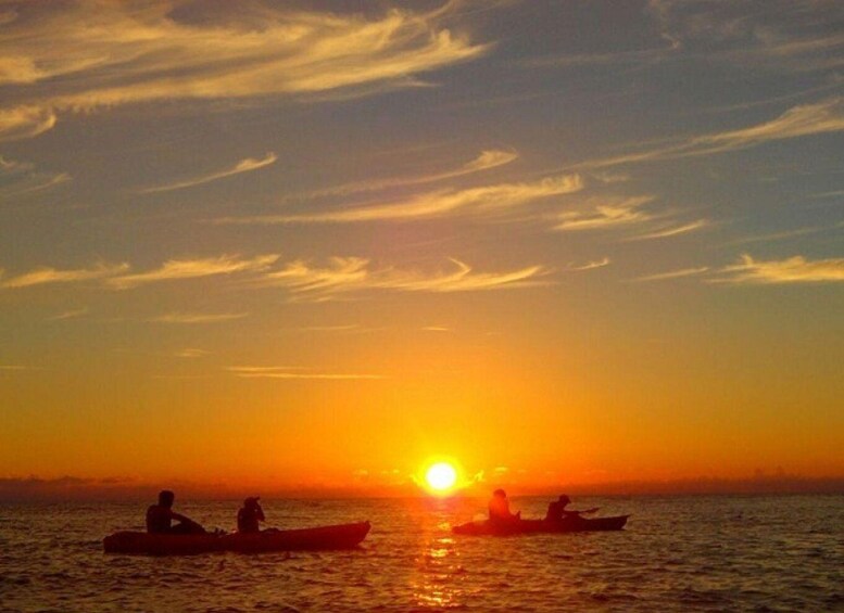 A sunset over the ocean with three boats. 5