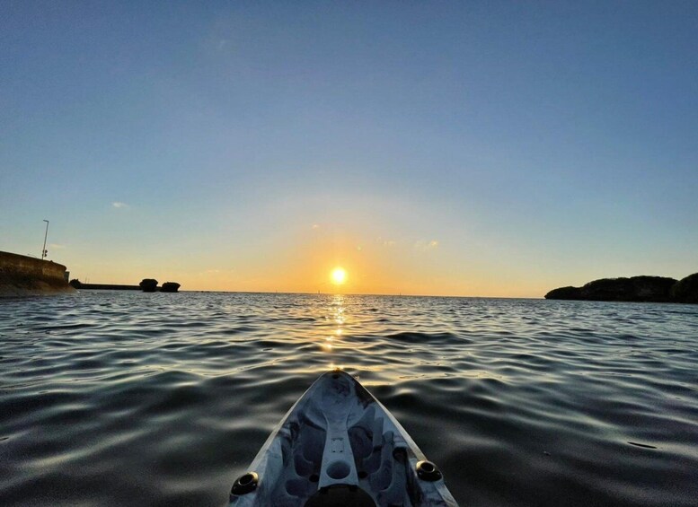 A kayak on calm water with the sun setting in the distance. 2