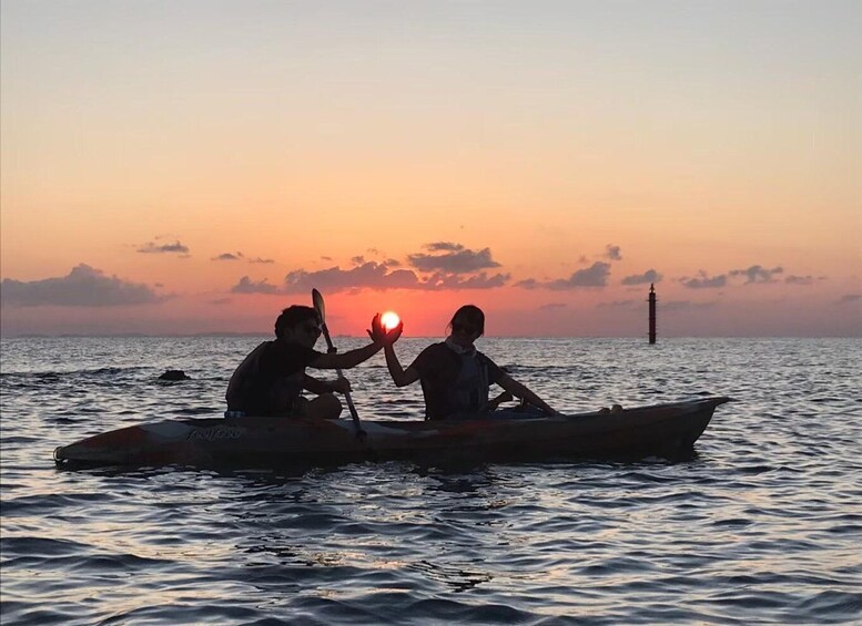 Two people in a boat on a body of water during sunset. 4
