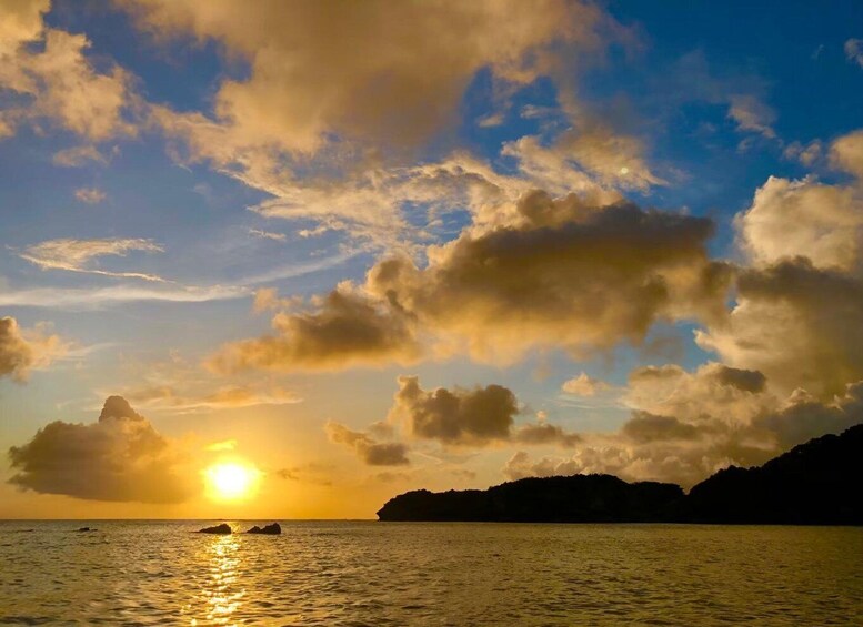 A sunset over a body of water with clouds and a distant landmass. 3