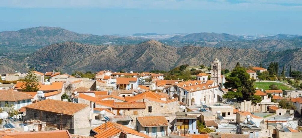 A mountainous town with terracotta-roofed buildings, a prominent church, and rolling hills in the background. 3